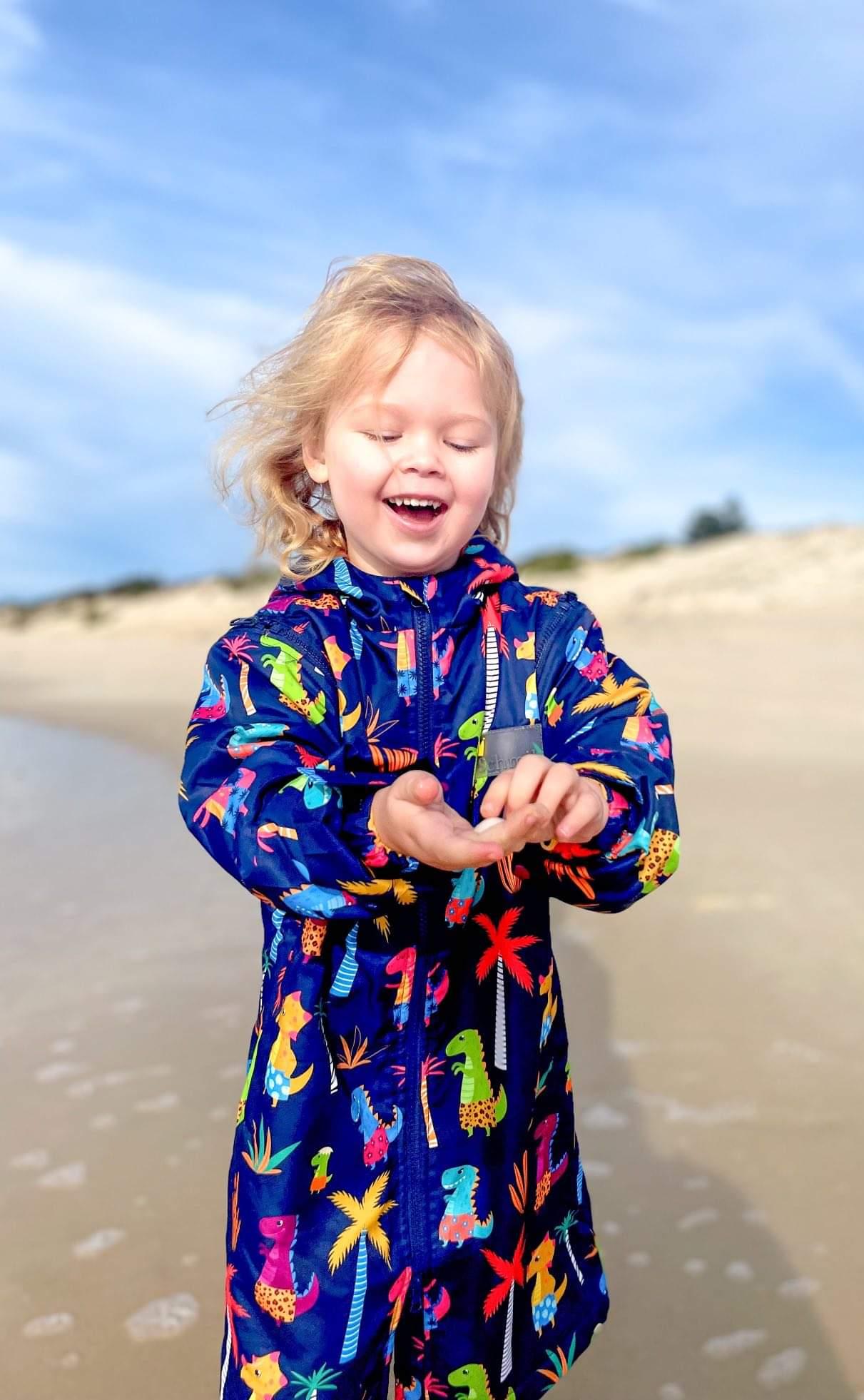 Beach swim parka worn by toddler on the beach. Swim parka is water resistant and keeps children warm after swimming. 