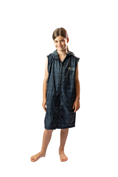 Child wearing a schmik swim parka in black. Black swim parka has removable sleeves and is zipped up.