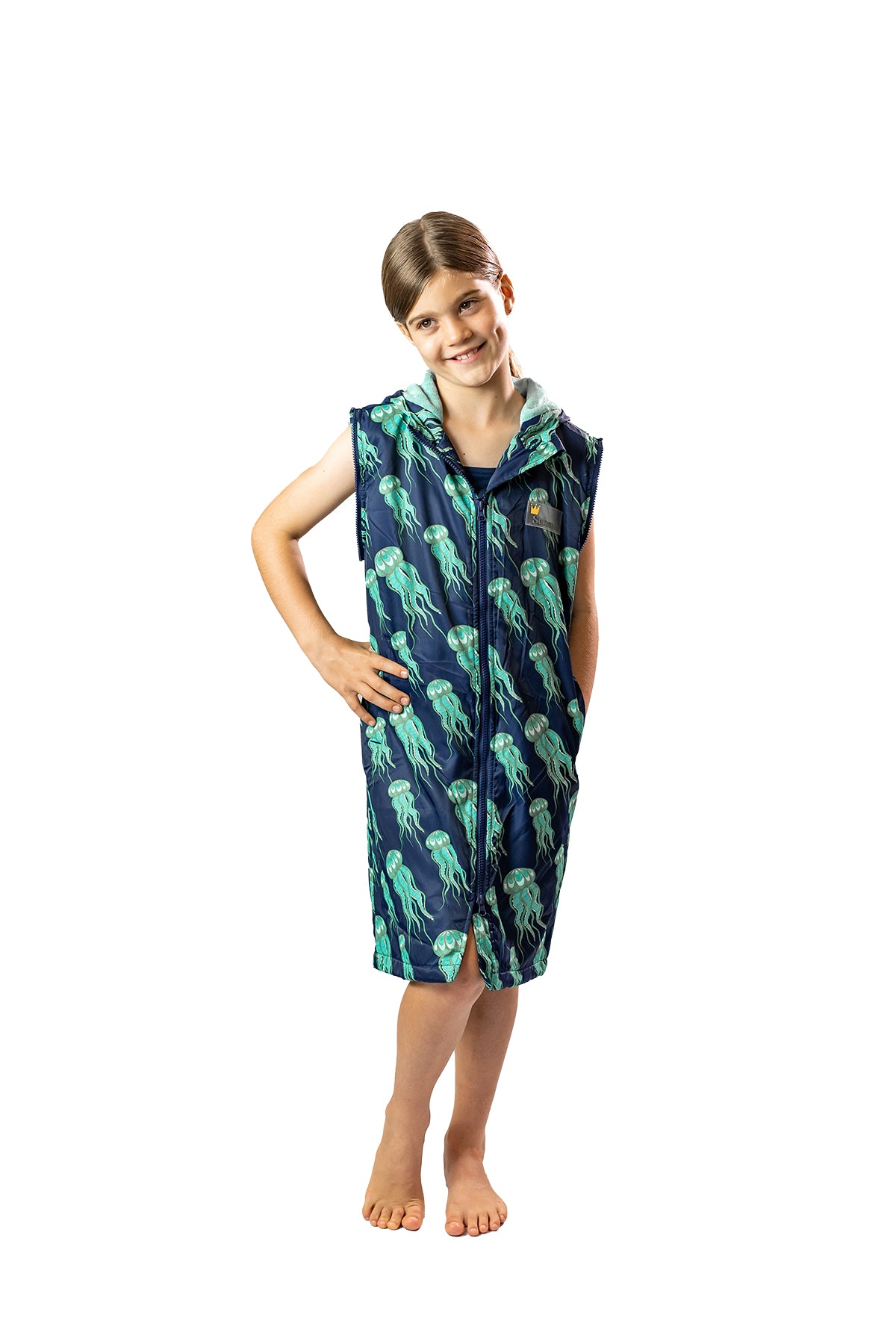 Child smiling, standing up wearing a schmik swim parka in jellyfish print. Swim parka has the arms removed. 