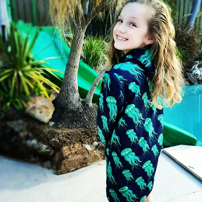 Child smiling wearing a schmik swim parka in jelly fish print. Schmik swim parkas come with removable arms so they can be worn in both summer and winter. 