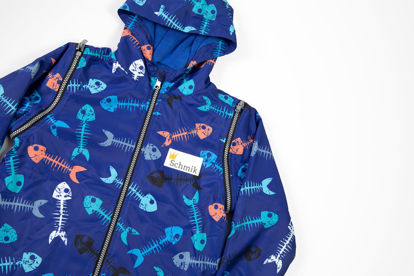 Close up picture of a schmik swim parka in fishbone print with blue colour. Swim parka shows removable arms that can be unzipped to be worn in both summe rand winter.